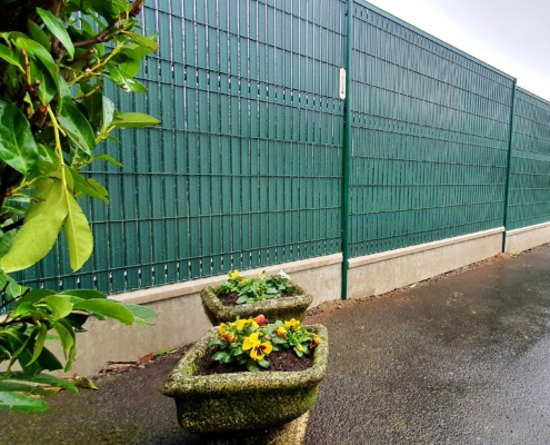 Clôture métallique avec panneau rigide, occultant vert et plaque béton